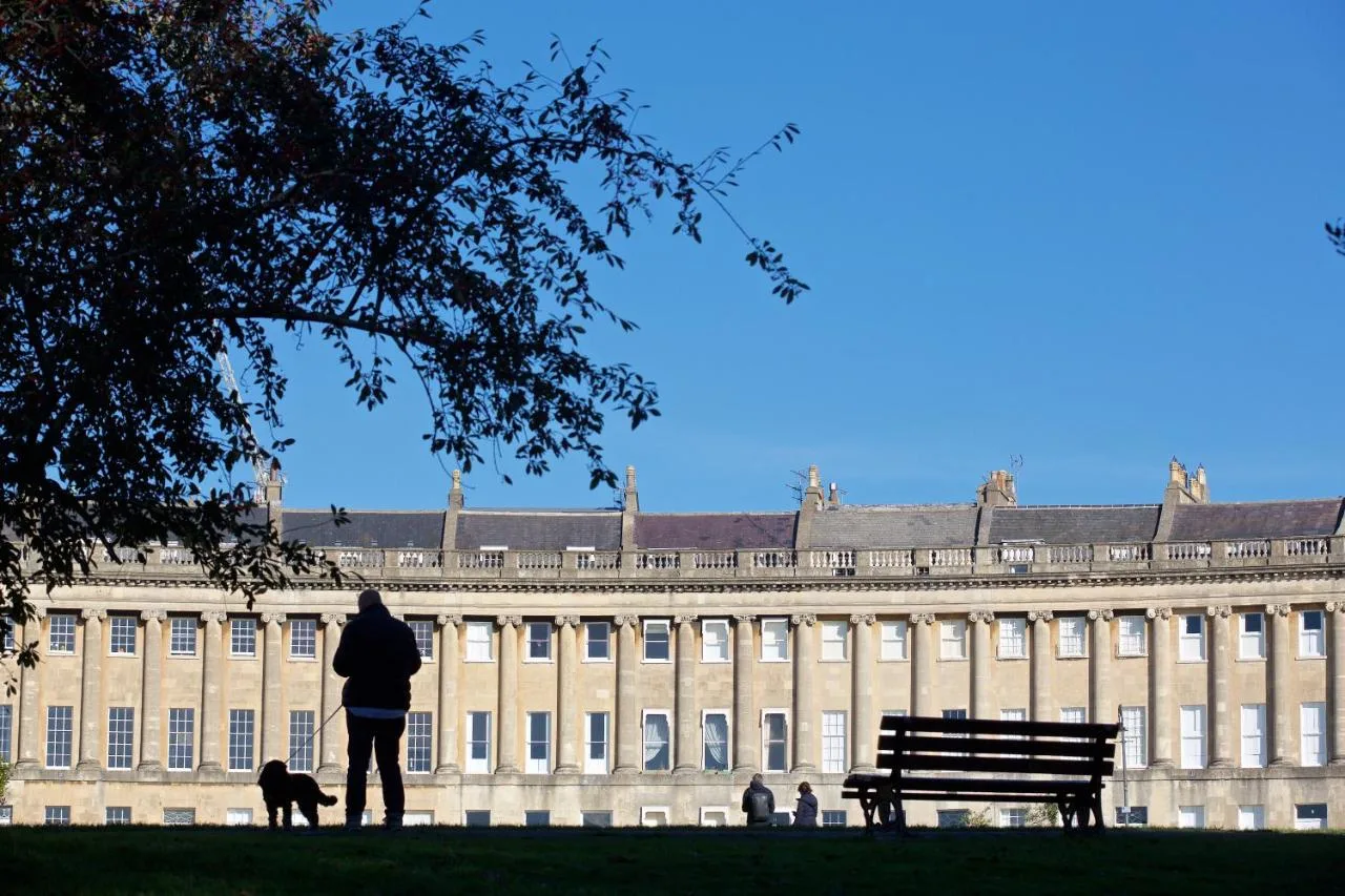 a person walking a dog in front of a building at The Z Hotel Bath in Bath